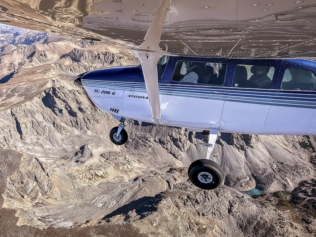 An airplane flies over a rock glacier located on the side of a mountain in the Rocky Mountain Range.